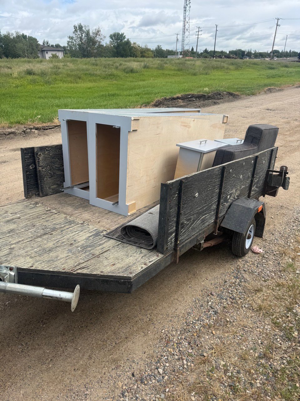 Utility trailer loaded with old cabinets and carpet for the landfill
