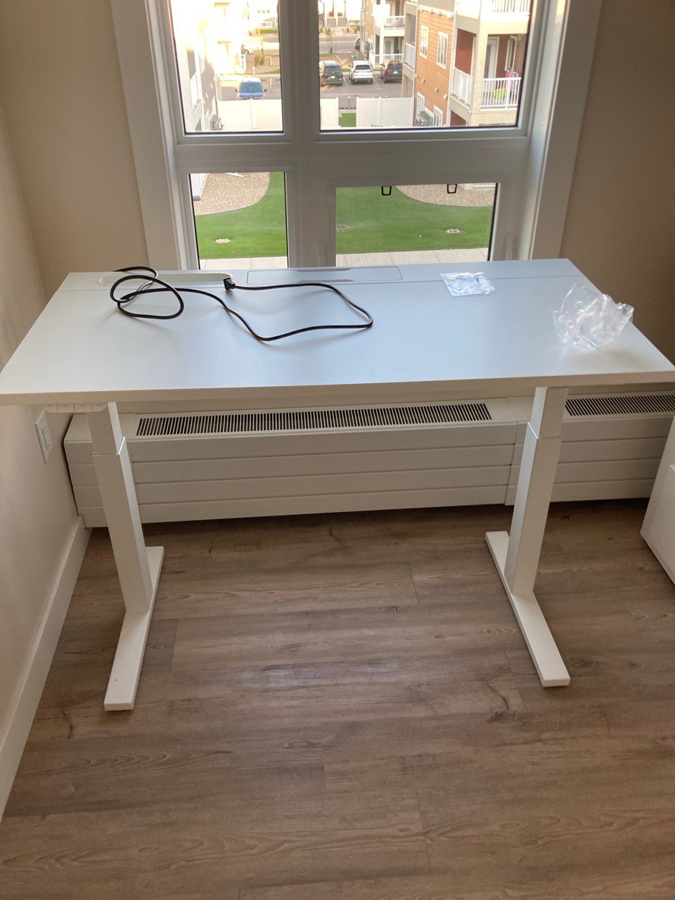 White height-adjustable standing desk assembled by a window